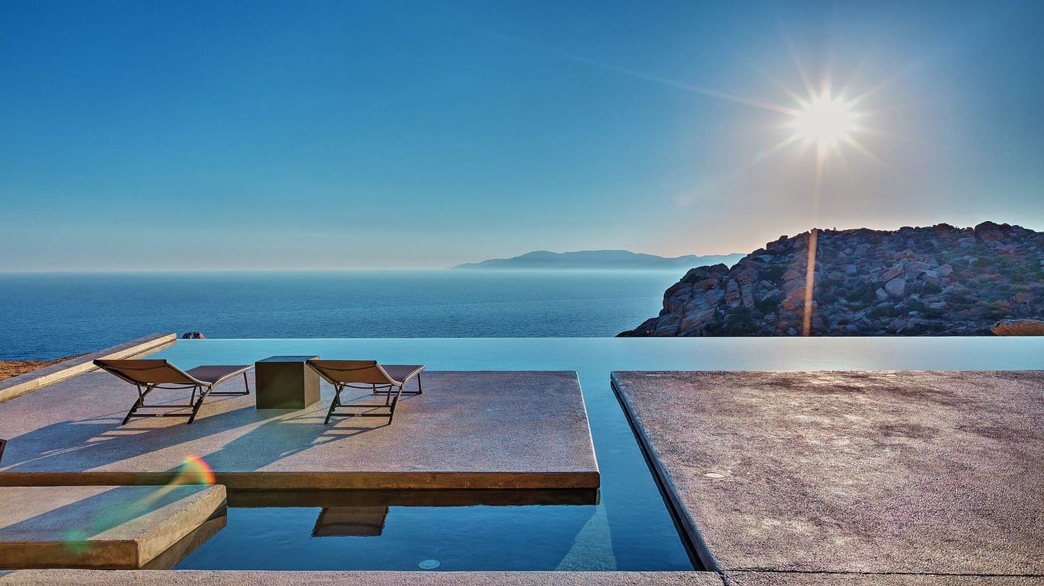 Transats au bord de la piscine à débordement de Villa Mylo, face à la mer Égée